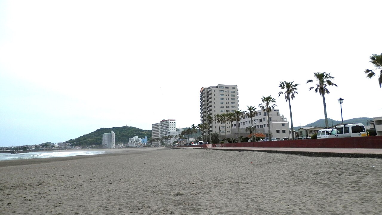 前原海岸の砂浜と海、ヤシが並ぶ舗装された遊歩道。