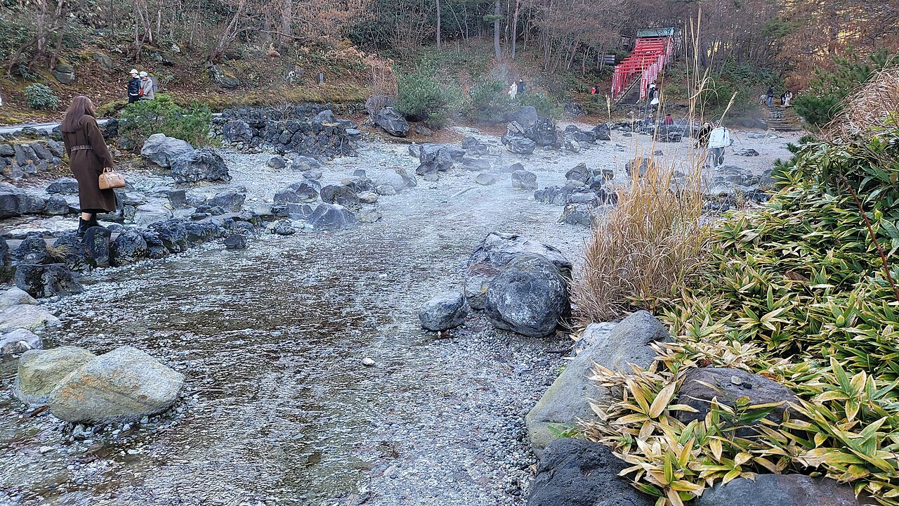 西の河原公園の岩と湯川、木々の間に立ち上る湯けむり。