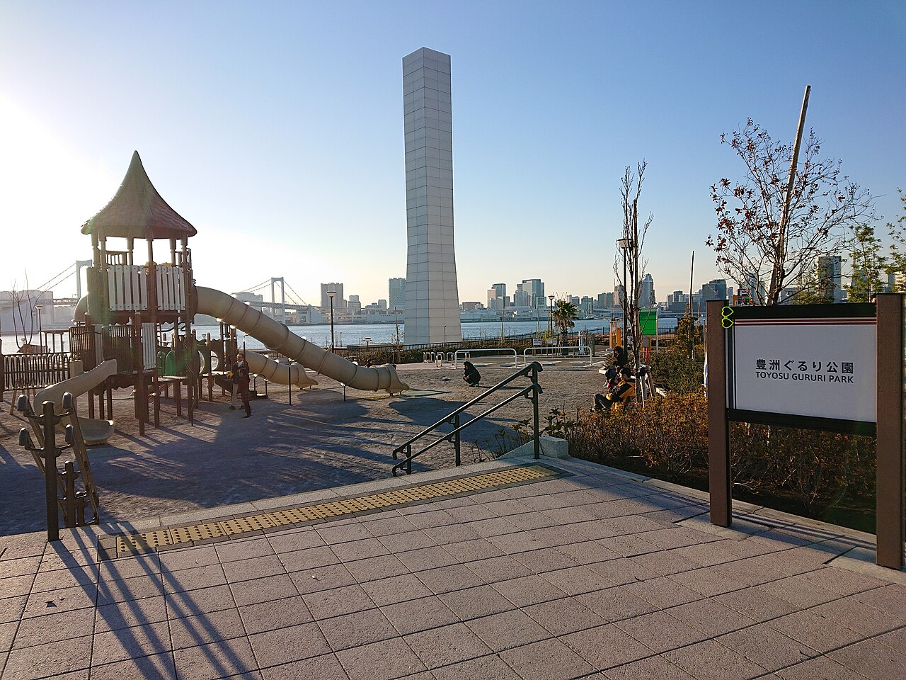 豊洲ぐるり公園の遊具広場。すべり台の奥に水辺とレインボーブリッジが見える。