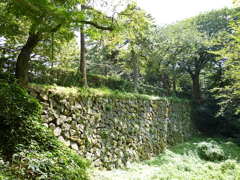 緑の木々に囲まれた高岡城跡の石垣。