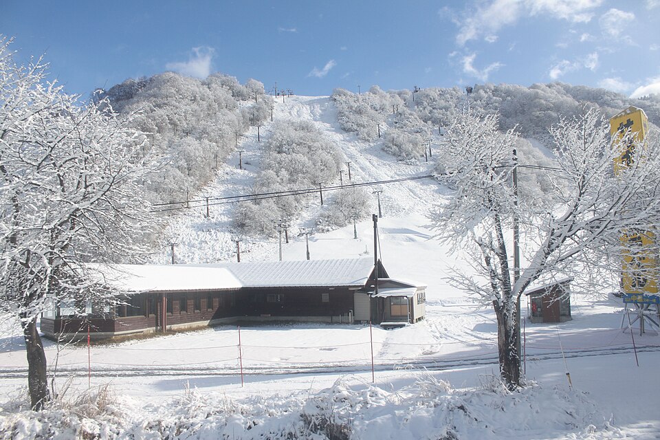 雪をまとった湯沢中里の斜面と麓の建物。
