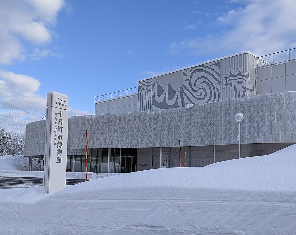 雪に囲まれた十日町市博物館の建物と館名標。